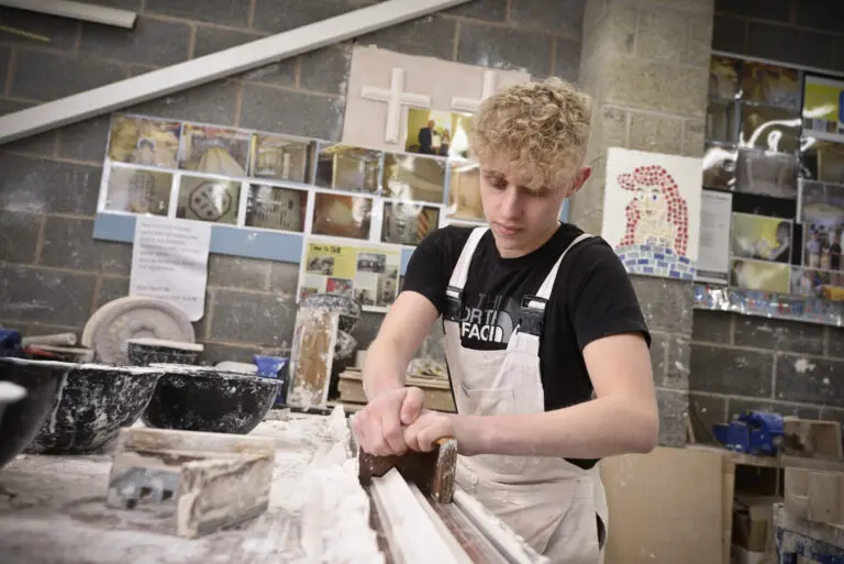 Student creating decorative molding in plaster